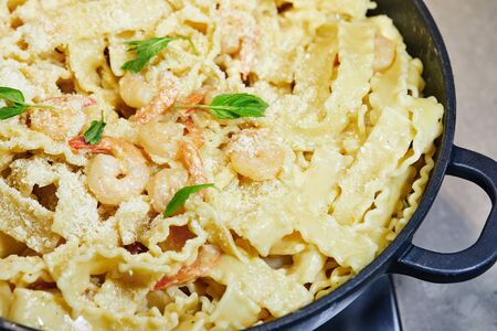 Fried prawns with Italian pasta called mafaldine, Parmesan cheese and herbs in a pan. View from above.の写真素材