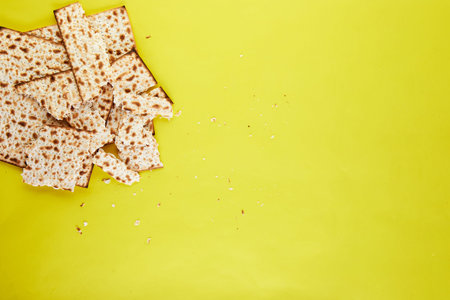 Pesah celebration concept - jewish Passover holiday. Matzo background broken into pieces on a yellow...