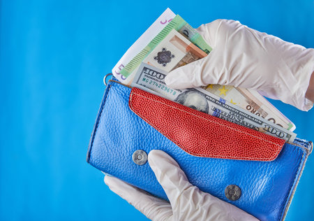 A woman taking money out of her wallet wearing rubber gloves to prevent the spread of bacterias or...