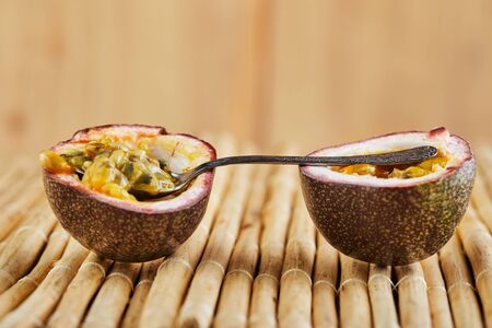 Passiflora is cut into two halves with a spoon inside on a bamboo background. Side view. Coppy spaceの写真素材
