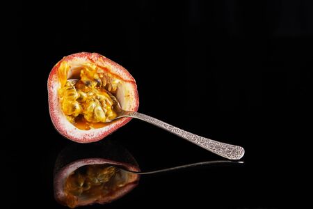 Passiflora half with a spoon inside isolated on a black background.の写真素材