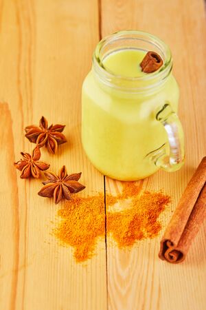 Golden milk with turmeric, cinnamon sticks, turmeric and anise on a gray cement background. Turmeric detox tea and ingredients. copy space.の写真素材