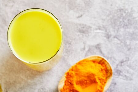 Golden milk with turmeric, cinnamon sticks, turmeric and anise on a gray cement background. Turmeric detox tea and ingredients. copy space.の写真素材