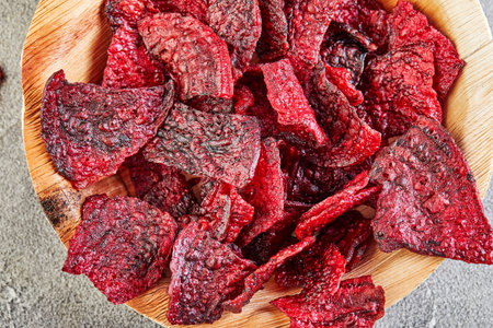 Diet healthy eating concept. Dried beet chips or baked beets in a wooden bowl, on a gray concrete background. Organic natural food.の写真素材