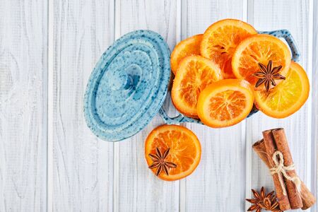 Slices of dried oranges or tangerines with anise and cinnamon in a blue bowl on a light background. Vegetarianism and healthy eating. Copy space. Flat lay.の写真素材
