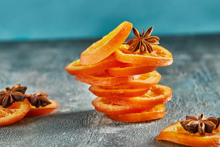 Slices of dried oranges or tangerines with anise and cinnamon, on a blue background. Vegetarianism...