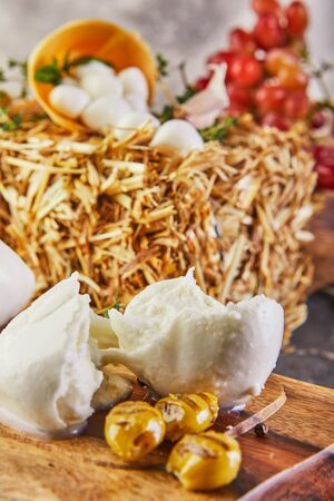 Fresca mozzarella with garlic and smoked olives on a wooden stand on a gray-blue background. Italian cheeses.の写真素材