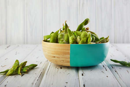 Frozen Edamame or soybeans in a wooden plate on a white wooden background.の写真素材