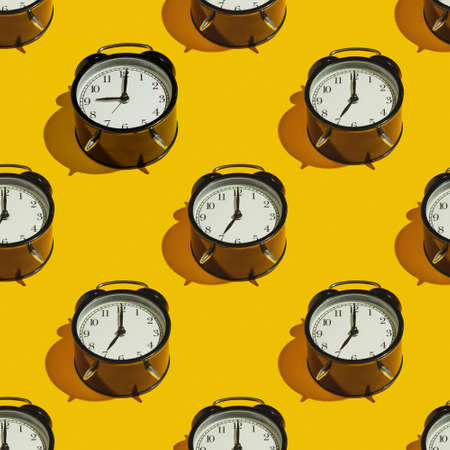 Pattern Black alarm clock with a hard shadow on a yellow background.の写真素材