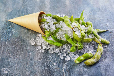 Frozen Edamame or soybeans in the mix with crushed ice on a blue background.の写真素材