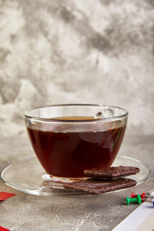 A cup of coffee with chocolate and colored pens, sheets of a diary with the inscription on a gray concrete background.の写真素材