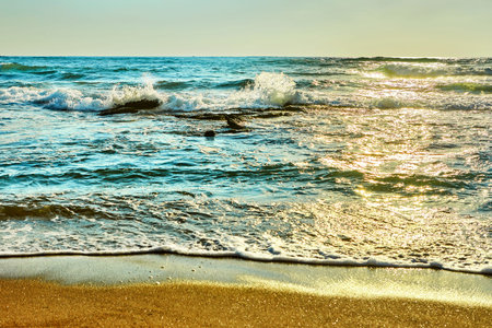 Sea surf with stones on the Mediterranean Sea during sunset.の写真素材