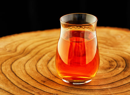 Exquisite Cognac in a special glass on a wooden stand on a black background.