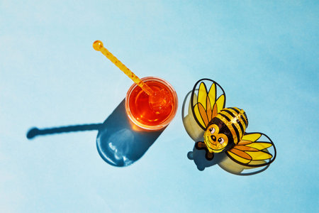 Jar with honey and shadow on a blue background, candy cane bee with shadow. The concept of the Rosh...