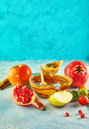 Rosh hashanah - jewish New Year holiday concept. Traditional symbols: Honey jar and fresh apples with pomegranate and shofar -horn on a blue background. Copy space for text.の写真素材