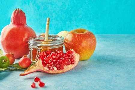 Rosh hashanah - jewish New Year holiday concept. Traditional symbols: Honey jar and fresh apples with pomegranate and shofar -horn on a blue background. Copy space for text.の写真素材