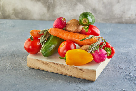 Various vegetables and fruits lying on a wooden podium, on a blue-gray background. Copy space for...