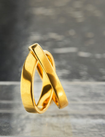 Wedding rings for women and men in yellow gold standing side by side on a gray shiny background.