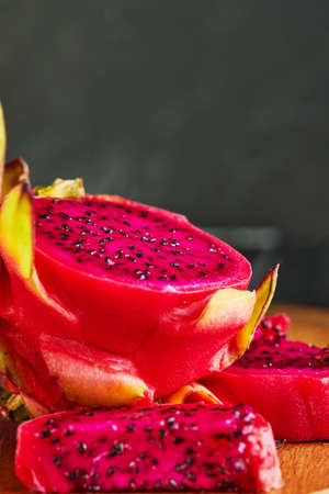Dragon fruit - pitahaya Cut into pieces on a wooden stand on a black wooden background.の写真素材