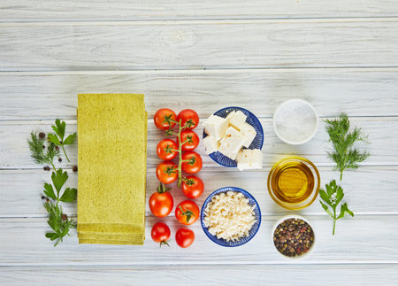 Sheets for making lasagna with spinach and ingredients: cherry tomatoes, cheese, butter, peppers and...