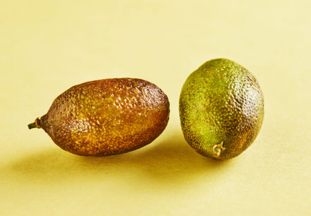 Ripe fresh mini lemons on a yellow background with a shadow.