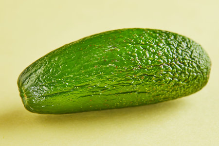 Ripe fresh mini avocado on a yellow background with shadow.