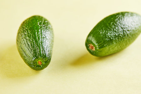 Ripe fresh mini avocado on a yellow background with shadow.