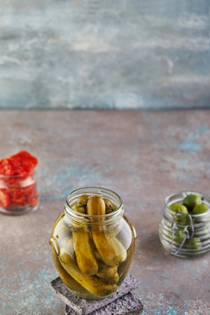 Fermented vegetarian canned food concept. Pickled cucumbers, olives, dried tomatoes in glass jars. The concept of canned food.の写真素材