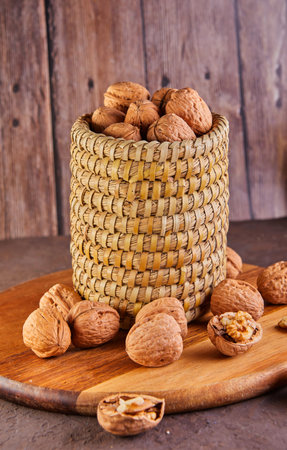 Walnuts in a wicker basket, whole and finely chopped, next to the filling and shells on a wooden background. Home storage of winter preparations.の写真素材