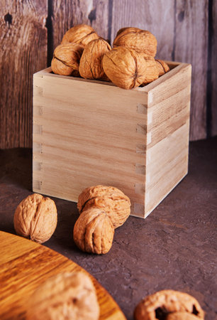 Walnuts in a wooden box, whole and finely chopped, next to the filling and shells on a wooden...