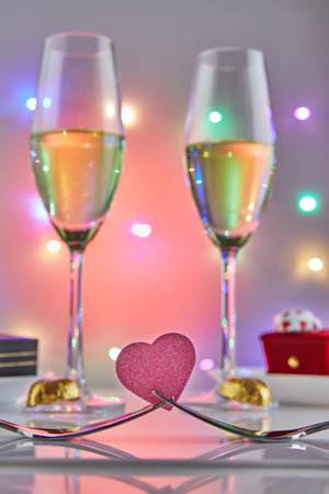 Valentines Day or romantic birthday dinner with candy hearts, glasses of champagne and elegant table setting with reflection and lights in the background.の写真素材