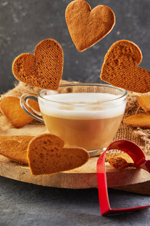 Heart shaped gingerbread cookies fall into a cup of coffee.の写真素材