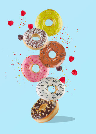 Food levitation - sweet colorful donuts flying in the air with raspberries and colored sprinkles.の写真素材