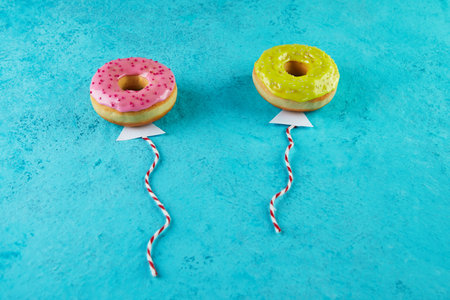 Multicolored donuts with glaze and sprinkles in the form of balloons flying in the sky.