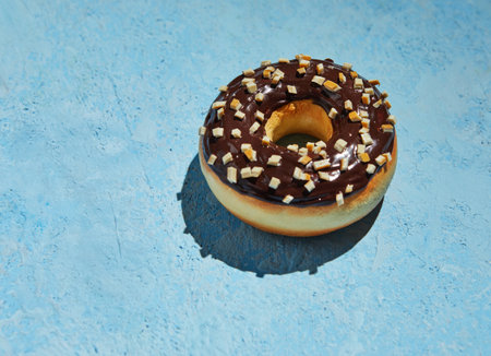 Donut with chocolate frosting and sprinkles on blue background.の写真素材