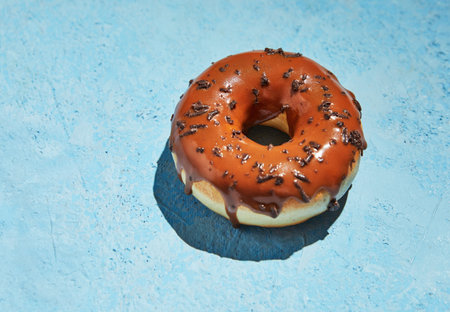 Donut with chocolate frosting and sprinkles on blue background.