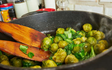 Cooking at home in the kitchen according to recipe from the Internet. Brussels sprouts are fried in pan. Step by step recipe.の写真素材