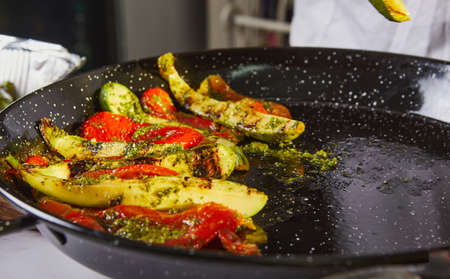 The chef prepares vegetarian salad with baked peppers, zucchini and parmesan cheese.の写真素材