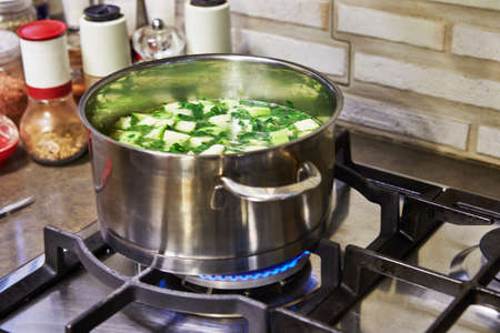 Cooking at home in the kitchen according to recipe from the Internet. Saucepan of boiling cream soup on the gas stove. Step by step recipe.の写真素材