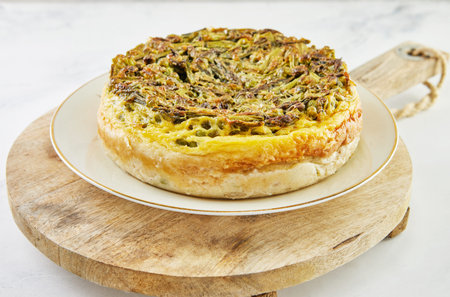 Pie with asparagus and peas on plate and wooden stand. Step by step recipe.