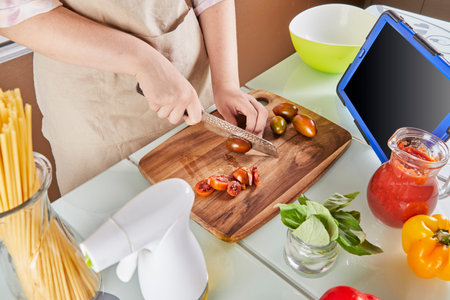 Teenager prepares virtual online tutorial on textbook and watches digital recipe on touchscreen...