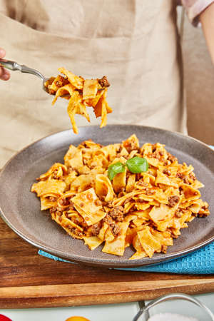 Cooked spaghetti bolognese from online learning using digital touchpad recipe, tastes the finished dish.の写真素材