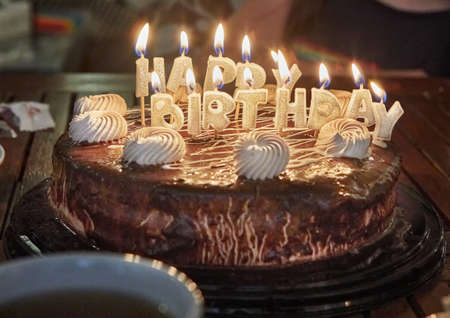 Cake with the inscription Happy Birthday with burning candles.の写真素材
