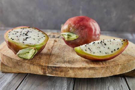 Peruvian apple cactus fruits whole and cut on wooden stand on gray board. Scientific name Cereus repandus.の写真素材