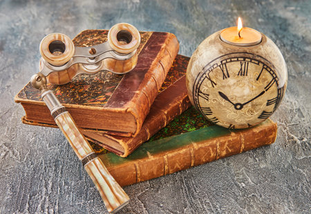 Still life with antique books, theatrical binoculars and candles in the shape of clockの写真素材