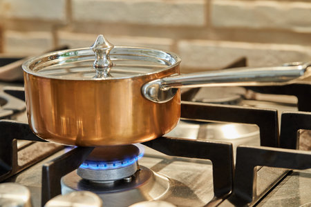 Copper saucepan over low heat on stove to make sauce.の写真素材