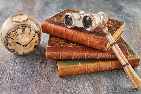 Still life with antique books, theatrical binoculars and candles in the shape of clockの写真素材