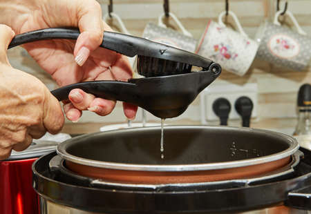 Chef squeezes lemon into pot of cooking food.の写真素材