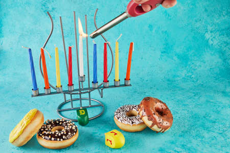 Happy Hanukkah and Hanukkah Sameach - traditional Jewish candlestick with candles, donuts and spinning tops on blue background.の写真素材