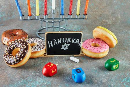 Happy Hanukkah and Hanukkah Sameach - traditional Jewish candlestick with candles, donuts and spinning tops with the inscription Hanukkah.の写真素材